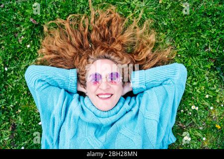 Portrait d'une femme mûre heureuse à tête rousse, couché sur l'herbe Banque D'Images