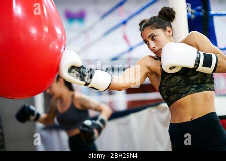 Boxeurs féminins s'entraîner au sac de punch dans la salle de gym Banque D'Images