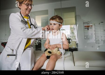 Pédiatre mesurant l’étendue de la tête de l’enfant Banque D'Images