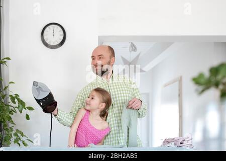 Père et fille repassant ensemble à la maison Banque D'Images