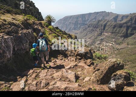 Vue arrière de père et petit fils avec sacs à dos marchant sur un sentier de randonnée dans les montagnes, la Gomera, îles Canaries, Espagne Banque D'Images