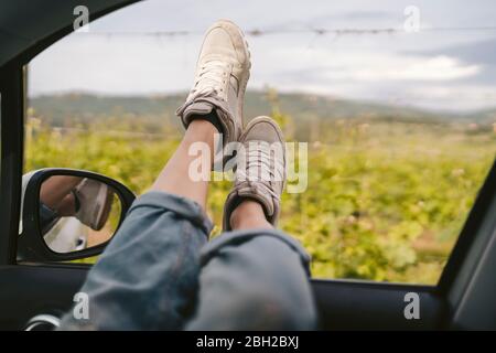 Pieds de femme se penchant hors de la fenêtre de voiture Banque D'Images