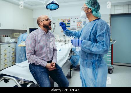 Médecin à l'hôpital prenant un écouvillon de la bouche du patient Banque D'Images