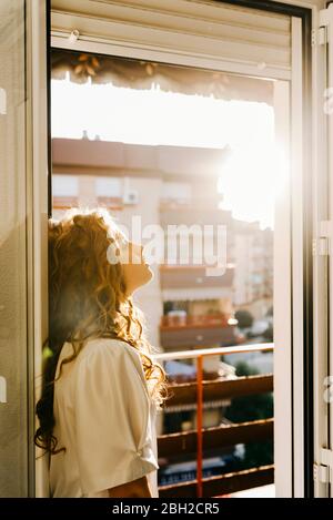 Portrait de la jeune femme blonde à la porte du balcon en contre-jour Banque D'Images
