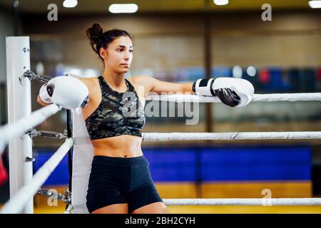 Boxeur féminin sportif dans l'anneau de boxe penchée sur la corde dans le coin Banque D'Images