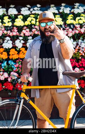 Portrait d'un homme barbu avec un vélo fixe qui dépasse la languette et affiche Rock and Roll Banque D'Images