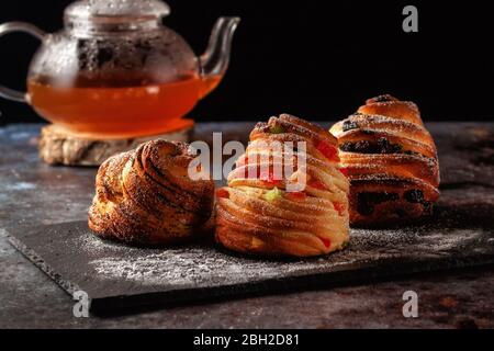 Kraffins aux raisins secs, fruits confits et graines de pavot, arrosés de sucre en poudre. Banque D'Images