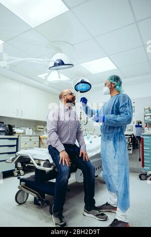 Médecin à l'hôpital prenant un écouvillon de la bouche du patient Banque D'Images