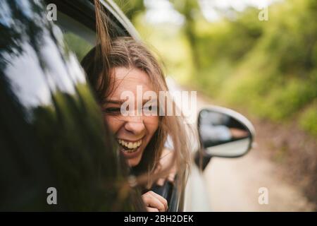 Carefree woman leaning out of car window Banque D'Images