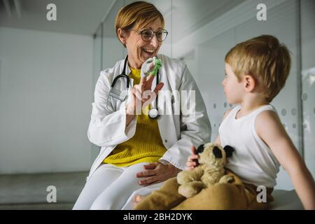 Peditricien avec des poupées de doigt et un tout-petit en pratique médicale Banque D'Images