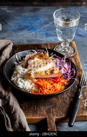 Bol de salade prête à consommer avec chou blanc et rouge, carottes, riz et schnitzel de poulet Banque D'Images