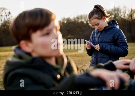 Frère et sœur avec téléphone cellulaire dans un pré Banque D'Images