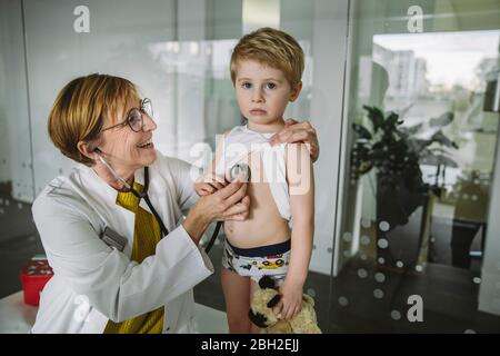 Médecin examinant un jeune garçon avec un stéthoscope Banque D'Images