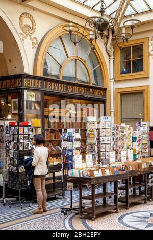 Jeune femme faisant du shopping dans une librairie ancienne du passage Vivienne, Paris, France