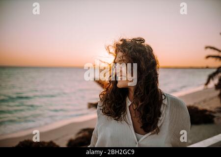 Femme profitant du lever du soleil à la mer Banque D'Images