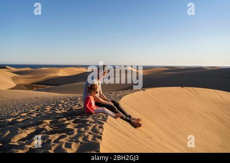 Père et fille assis sur une dune de sable, Gran Canaria, Espagne Banque D'Images