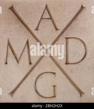 Inscription AMDG (Ad Majorem Dei Gloriam) sur le mur de Kensington de St Columba, Londres; bâtiment de l'église d'Écosse conçu par Sir Edward Maufe, 1955 Banque D'Images