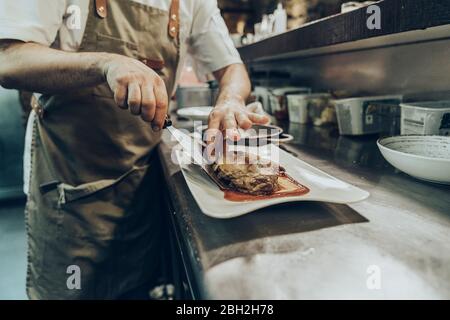 Chef s'occupant de plats sur les assiettes avant de servir au restaurant Banque D'Images