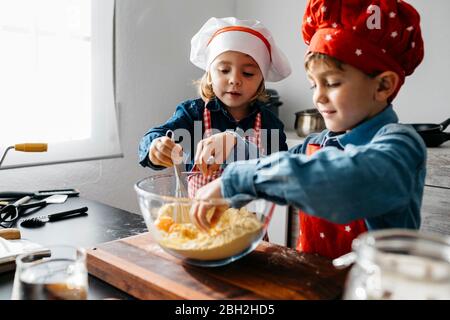 Frère et sœur préparant de la pâte dans la cuisine à la maison Banque D'Images