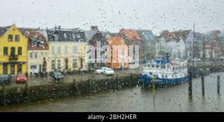 Allemagne, Schleswig-Holstein, Husum, maisons au bord de l'eau vues à travers des fenêtres de verre couvertes de raindrops Banque D'Images