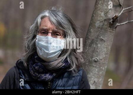 Femme âgée posant dans un masque de protection, banlieue de Boston, Massachusetts, États-Unis Banque D'Images