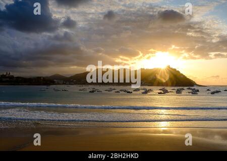 Espagne, Gipuzkoa, San Sebastian, Bateaux flottant dans la baie de la Concha au coucher du soleil nuageux Banque D'Images