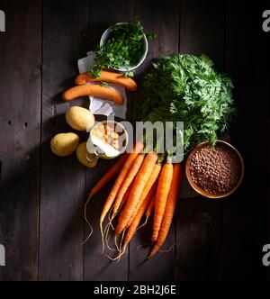 Bouquet de carottes, saucisses, persil, pommes de terre, soupe de lentilles en conserve et bol de lentilles Banque D'Images