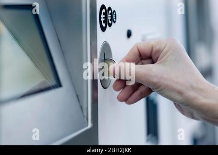 Main de femme mettant la pièce dans la machine à payer Banque D'Images