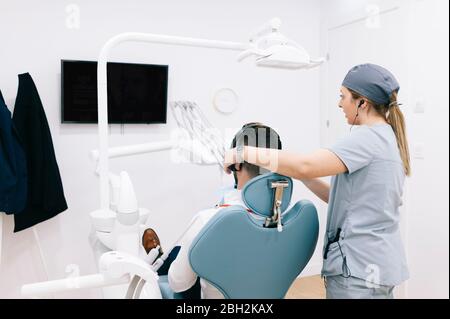 médecin préparant un traitement dentaire en mettant des écouteurs sur la tête du patient Banque D'Images