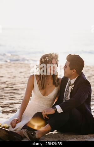 Couple de mariés heureux assis à la plage Banque D'Images