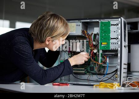Femme assemblant un pc de bureau au bureau Banque D'Images