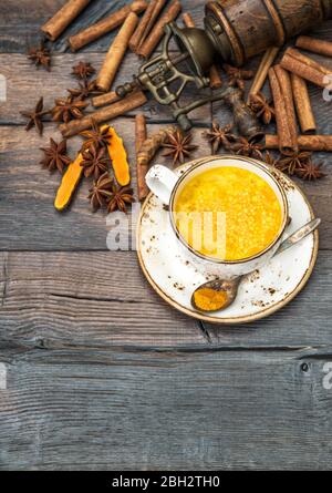 Lait d'or. Boisson chaude au curcuma avec épices sur fond rustique en bois Banque D'Images