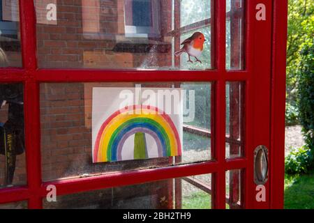 Talabour, Buckinghamshire, Royaume-Uni. 23 avril 2020. Un dessin arc-en-ciel pour enfant avec le clocher de l'église St Nicholas Spire et un autocollant de vol sur une ancienne boîte téléphonique rouge à Talaplow High Street pendant le verrouillage de la pandémie de Coronavirus. Crédit : Maureen McLean/Alay Live News Banque D'Images