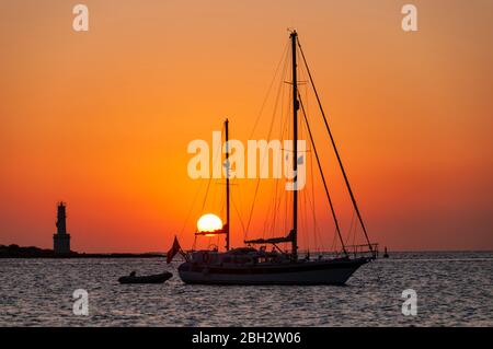 Voiliers au coucher du soleil ancré dans la baie près du phare. Magnifique coucher de soleil sur la mer Méditerranée dans l'île de Formentera Espagne Banque D'Images