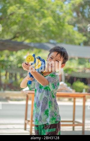 Un garçon asiatique tenant un pistolet à eau joue au festival Songkran en Thaïlande. Banque D'Images