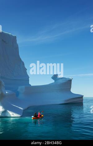 Un couple faisant du kayak autour d'un iceberg au Groenland en été Banque D'Images