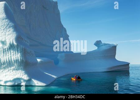 Un couple faisant du kayak autour d'un iceberg au Groenland en été Banque D'Images