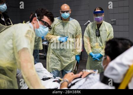 Les soldats affectés à la station médicale de New York de Javits au Centre de congrès Jacob K. Javits de New York effectuent des procédures d’enregistrement sur un patient entrant de la COVID-19 dans la baie médicale de l’établissement. Banque D'Images