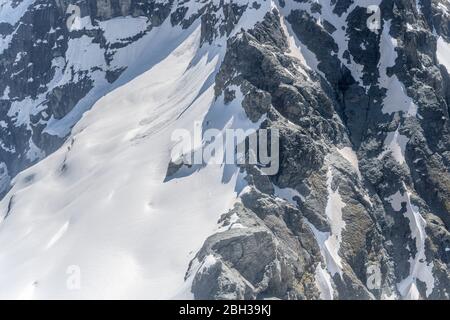 Aérien, à partir d'un planeur, de bord de la crête sombre abrupte à Mt. La hauteur de la tête avec neige printanière, filmée dans une lumière de printemps vive du nord-est, Otago, South Islan Banque D'Images