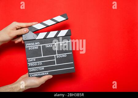 Clapper de film dans les mains d'un gars sur un fond rouge avec place pour le texte Banque D'Images