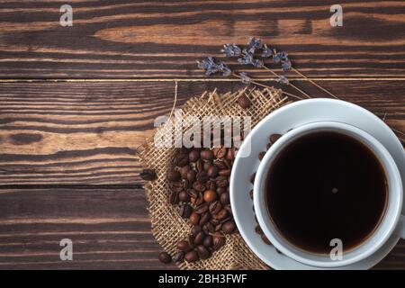Tasse avec café noir, grains de café et branches de lavande sur un plan d'examen en bois. Vue de dessus. Banque D'Images