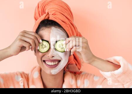 Jeune femme ayant soin de la peau spa jour à la maison - heureuse fille appliquant le masque de nettoyage du visage de concombre Banque D'Images