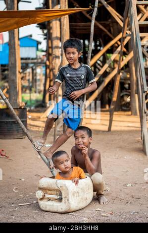 Trois jeunes garçons cambodgiens partagent une blague en jouant dans la rue du village flottant de Kampong Phluk, au Cambodge. Banque D'Images