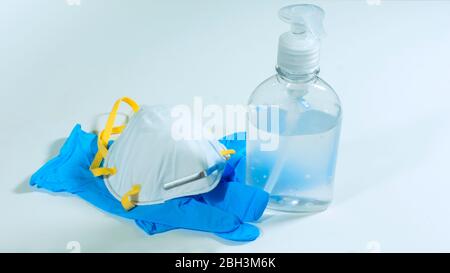 Vue rapprochée de la bouteille en plastique avec gel d'alcool, masque facial blanc et gants en latex bleu sur fond blanc Banque D'Images