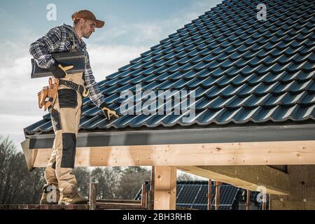 Toiture caucasienne mâle installation de tuiles de toiture sur maison nouvellement construite. Banque D'Images