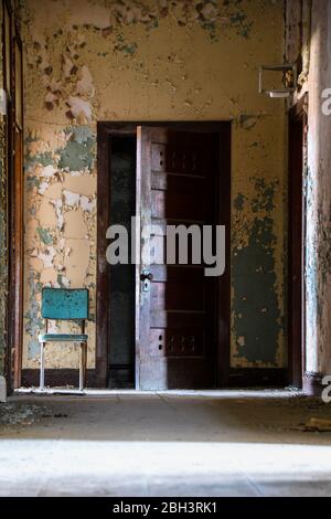 Chaise et porte dans le couloir d'un hôpital abandonné Banque D'Images