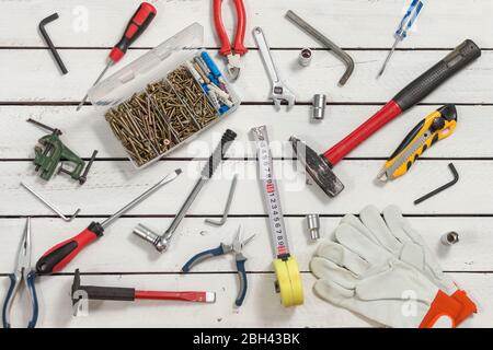 Les outils de menuisier se répandent sur une table en bois faite de panneaux blancs. Banque D'Images