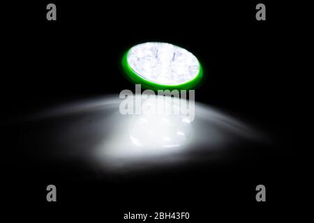 Lampe torche LED verte qui brille sur une surface blanche dans une pièce sombre Banque D'Images