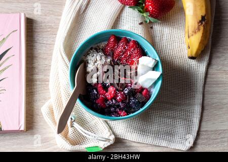 Bol à smoothie sain avec granola, fraises fraîches, bleuets, noix de coco, banane, chocolat, yaourt et graines de chia. Une alimentation saine Banque D'Images