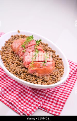 Grand cotéchino italien à saucisses de porc servi avec des lentilles. Plats de Noël traditionnels d'Italie. Un bol de nourriture sur une plaque. Photo de haute qualité Banque D'Images